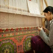 A weaver working at a carpet loom